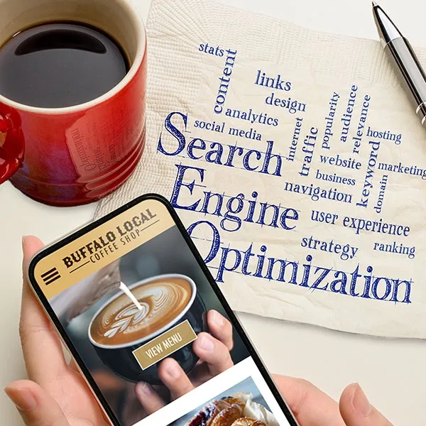 Search Engine Optimization cloud written on napkin next to a mobile phone with a responsive website.