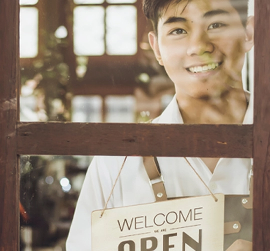 man in retail shop window with welcome open sign